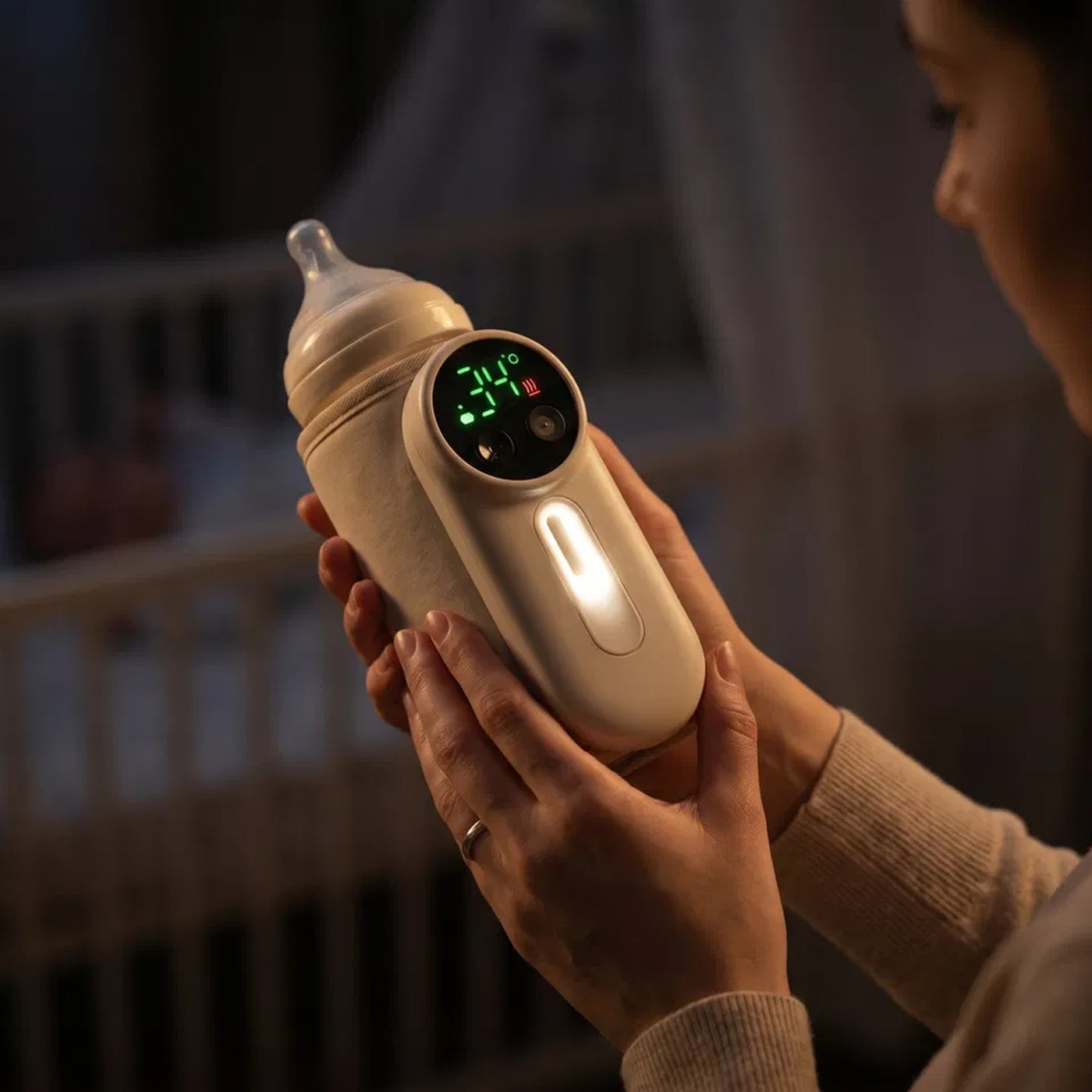 Mother holding ZuzuNest bottle warmer in a dark nursery at night — view 2
