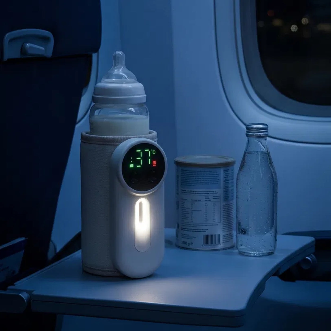 ZuzuNest bottle warmer on an airplane tray table during night travel — view 7